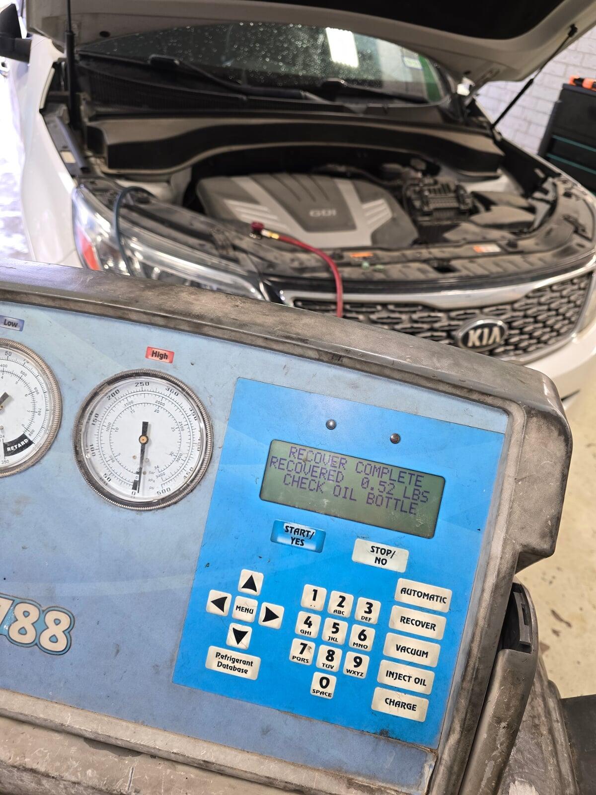 air conditioning recharge machine servicing a Kia car.
