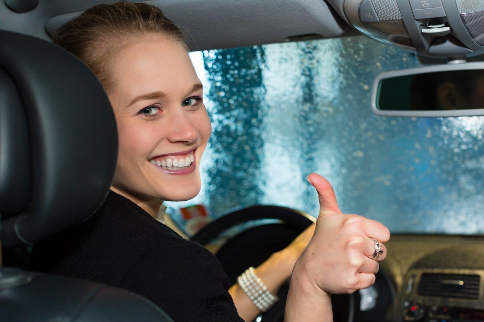 Woman giving a thumbs up while sitting in her car for an oil change.